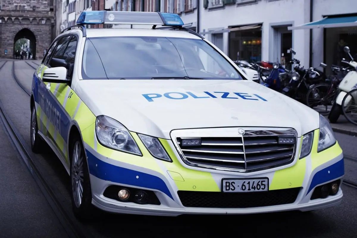 Ein Polizeiauto mit dem Schild 'Polizei' steht auf einer Straße in einer Altstadt. Mehrere Fahrräder sind im Hintergrund zu sehen.