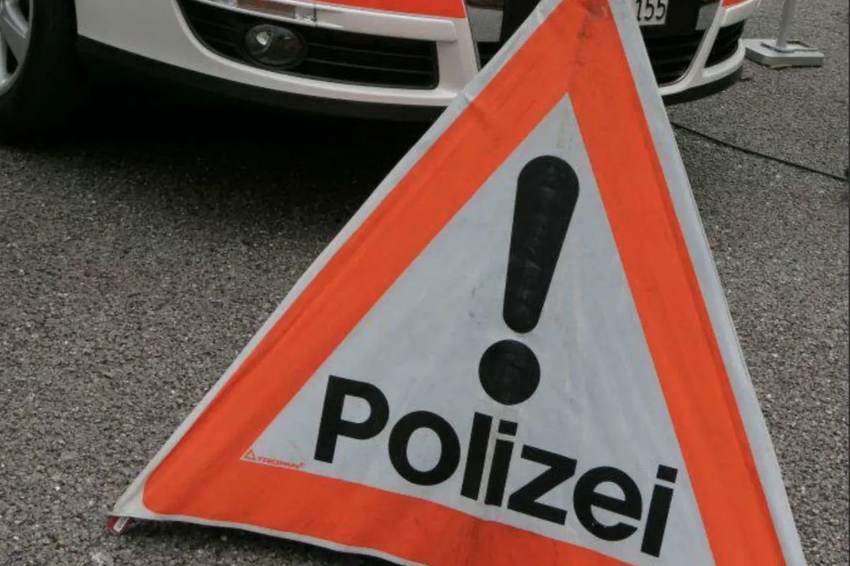 Ein Warndreieck mit orangefarbener Umrandung und dem Wort 'Polizei' steht vor einem weißen Polizeiauto. Das Warndreieck zeigt ein schwarzes Ausrufezeichen.