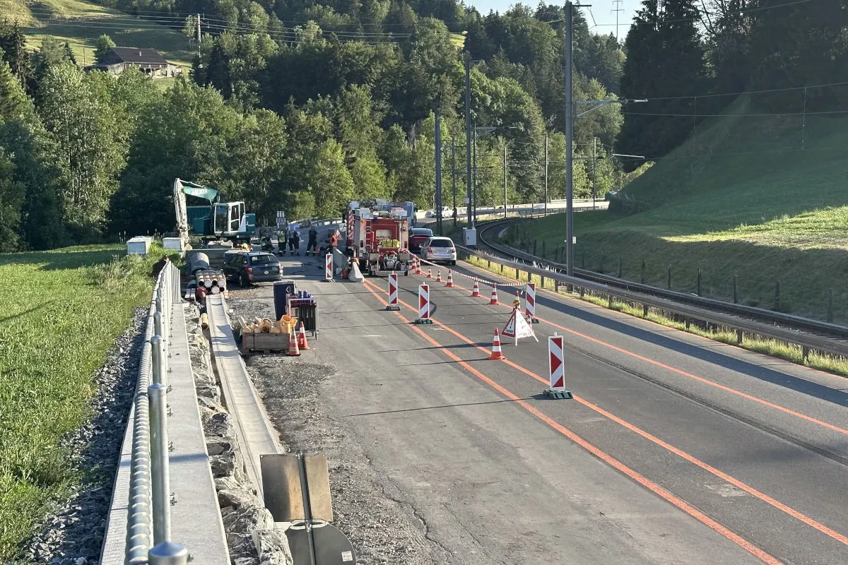 Eine Landstraße ist durch Absperrungen begrenzt. Ein Einsatzfahrzeug steht auf der Fahrbahn, während Bauarbeiten stattfinden.
