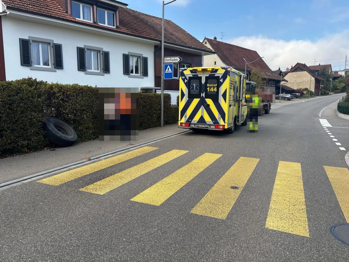 Ein Krankenwagen mit der Notrufnummer 144 steht auf einer Dorfstraße neben einem Zebrastreifen. Im Hintergrund sind Häuser zu sehen.