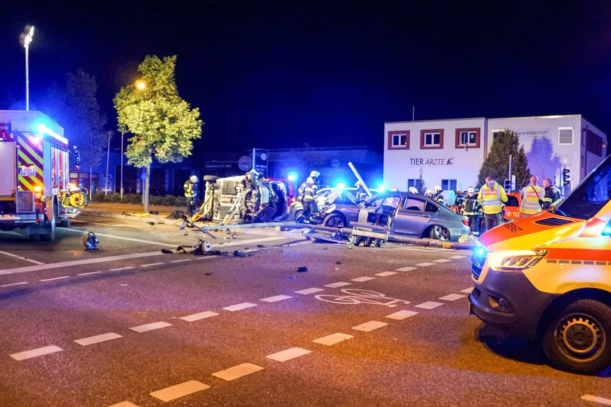Ein schwerer nächtlicher Autounfall an einer Kreuzung mit mehreren beschädigten Fahrzeugen und Einsatzkräften vor Ort.