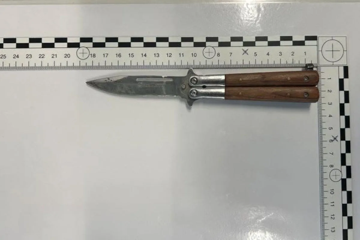 Ein Messer mit Holzgriff liegt geöffnet neben einem Maßband auf einer weißen Oberfläche. Das Maßband zeigt Zentimeter an.