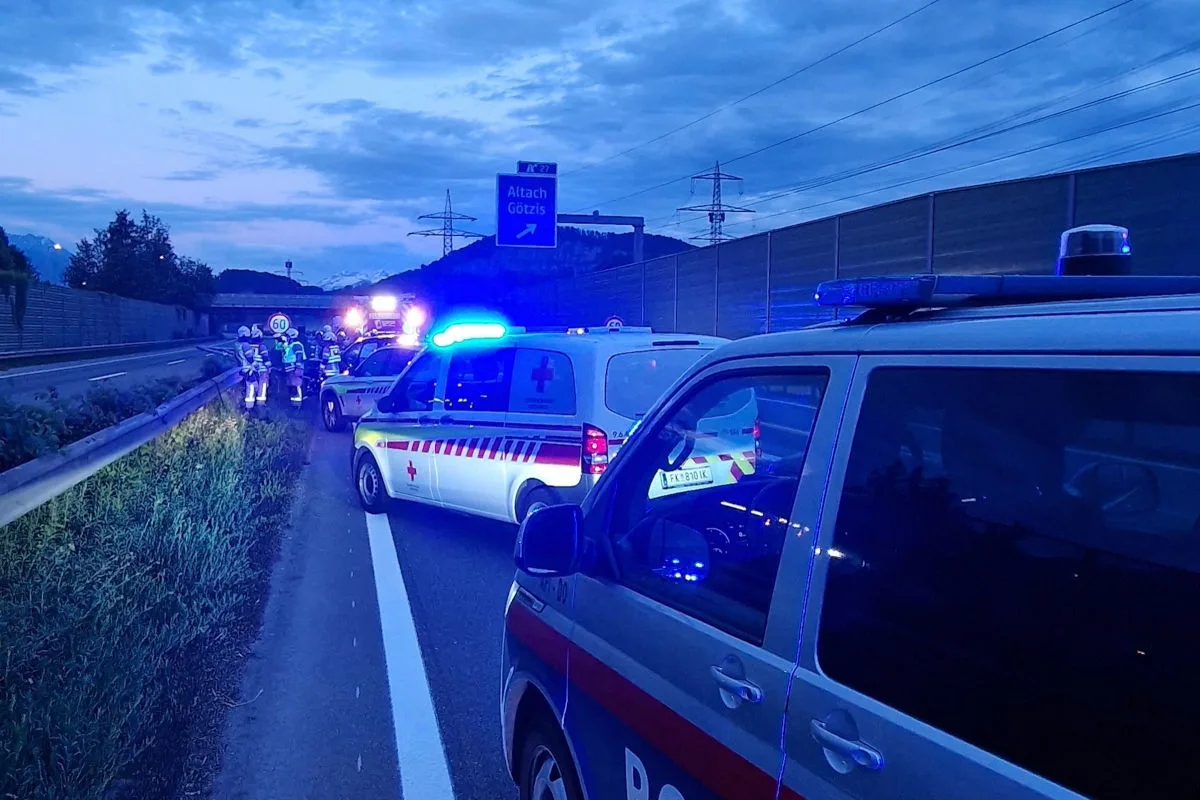Mehrere Polizei- und Rettungsfahrzeuge stehen mit eingeschaltetem Blaulicht auf einer Autobahn. Im Hintergrund ist ein Straßenschild mit der Aufschrift 'Altach Götzis'.