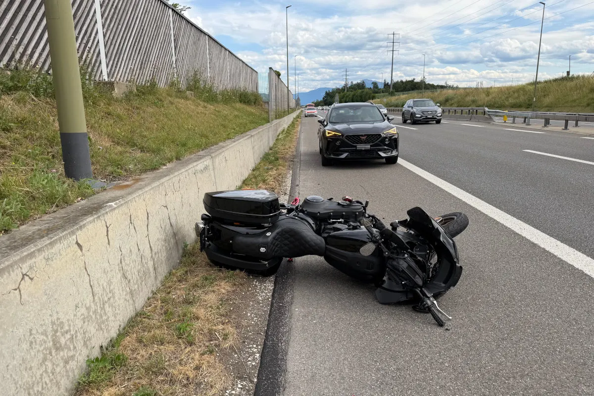 Ein schwarzes Motorrad liegt umgestürzt auf dem Seitenstreifen einer Autobahn. Mehrere Autos fahren auf der Straße im Hintergrund.
