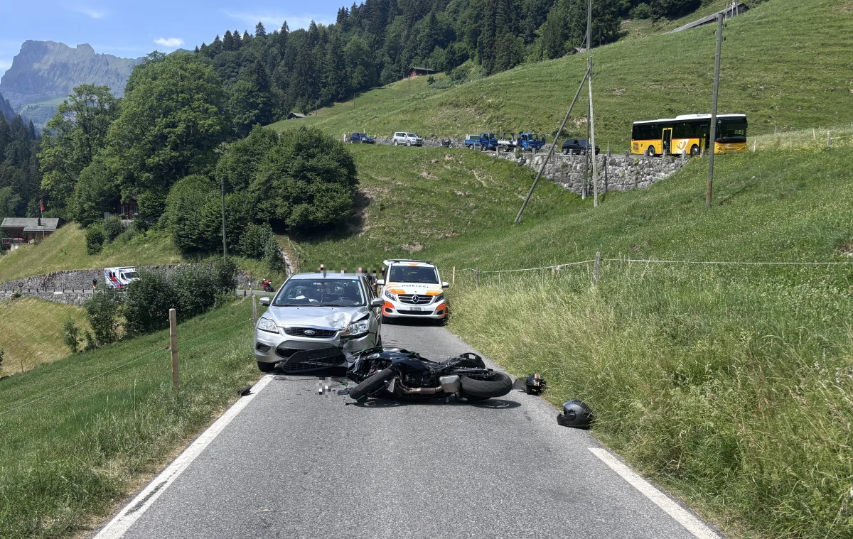 Ein Pkw und ein Motorrad liegen nach einer Kollision auf einer schmalen Landstraße. Im Hintergrund sind ein Polizeifahrzeug und ein Bus zu sehen.