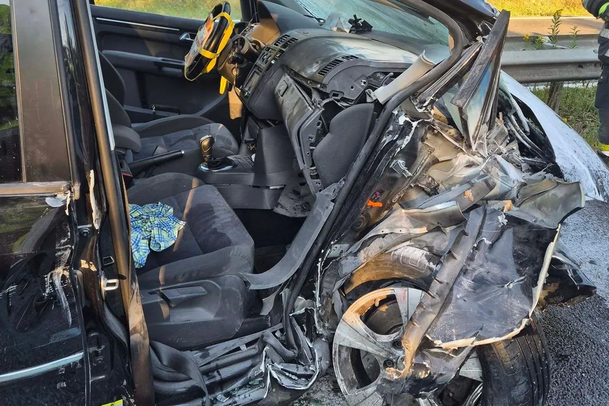 Das Bild zeigt das Innere eines Fahrzeugs nach einem schweren Unfall. Die Türen sind geöffnet, und das Lenkrad ist ungewöhnlich nach vorne geklappt.