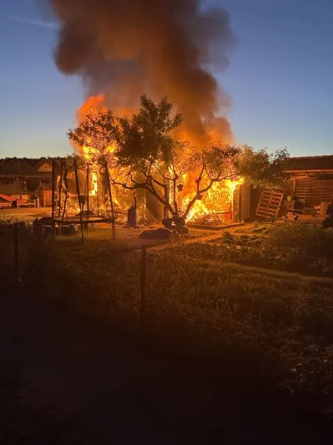 Ein großes Feuer erfasst ein Gebäude in der Nacht, während Flammen hochschlagen und dichter Rauch aufsteigt.