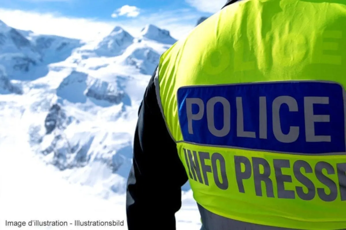 Ein Polizist in einer gelben Weste steht vor einer winterlichen Bergkulisse. Im Hintergrund sind schneebedeckte Gipfel sichtbar.