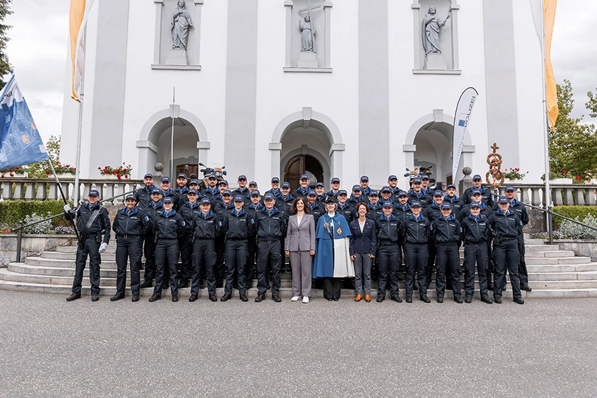 Eine große Gruppe von Polizisten in Uniform steht vor einem historischen Gebäude mit Statuen in Nischen.