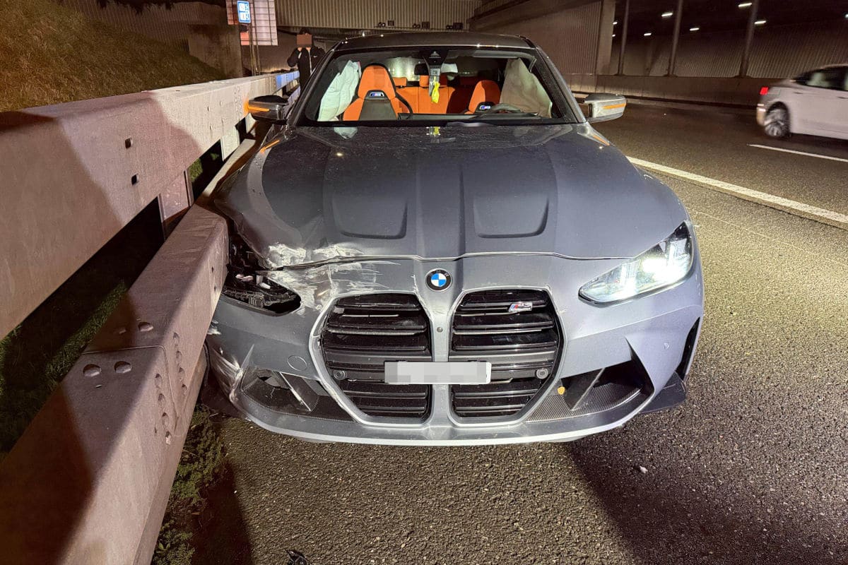 Ein BMW mit sichtbaren Frontschäden steht direkt an der Leitplanke einer Autobahn. Die Airbags sind ausgelöst.