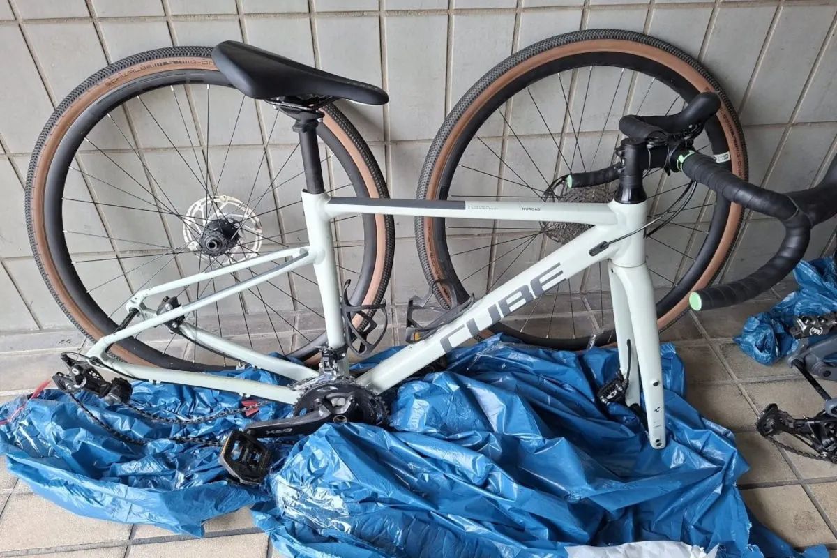 Ein Fahrrad in Einzelteilen liegt auf einer blauen Plane in einem gefliesten Innenraum.