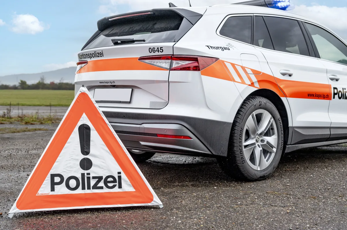 Im Bild sieht man ein Polizeifahrzeug der Kantonspolizei Thurgau neben einem aufgestellten Warnschild mit Aufschrift 'Polizei'. Der Himmel ist leicht bewölkt.