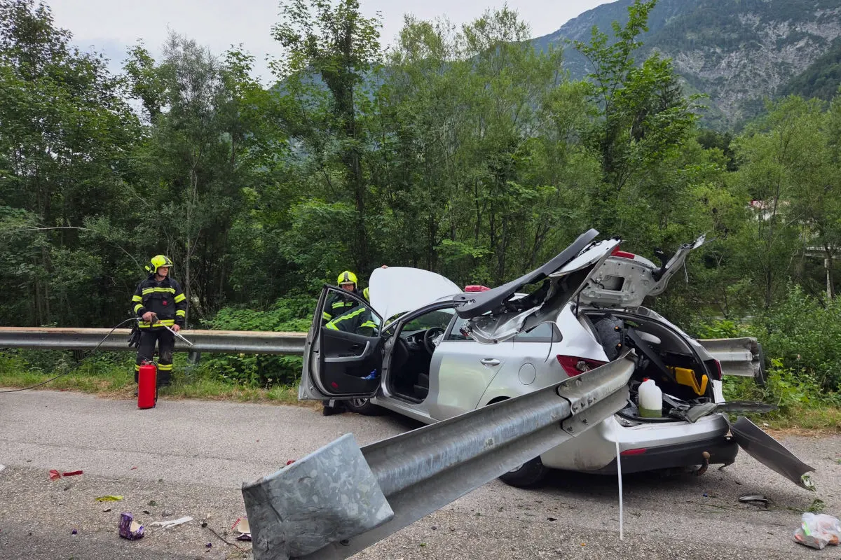 Ein weißes Auto hat eine erhebliche Kollision mit einer Leitplanke erlebt. Feuerwehrleute in voller Montur sind vor Ort und sichern die Unfallstelle.