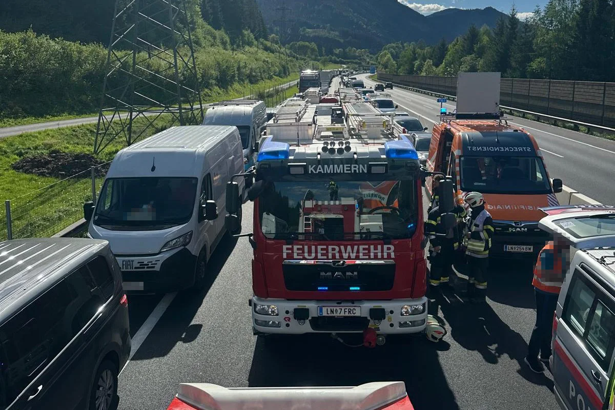 Mehrere Einsatzfahrzeuge und einige Einsatzkräfte sind auf einer Autobahn versammelt. Ein Feuerwehrauto mit der Aufschrift 'FEUERWEHR' steht im Mittelpunkt des Bildes.