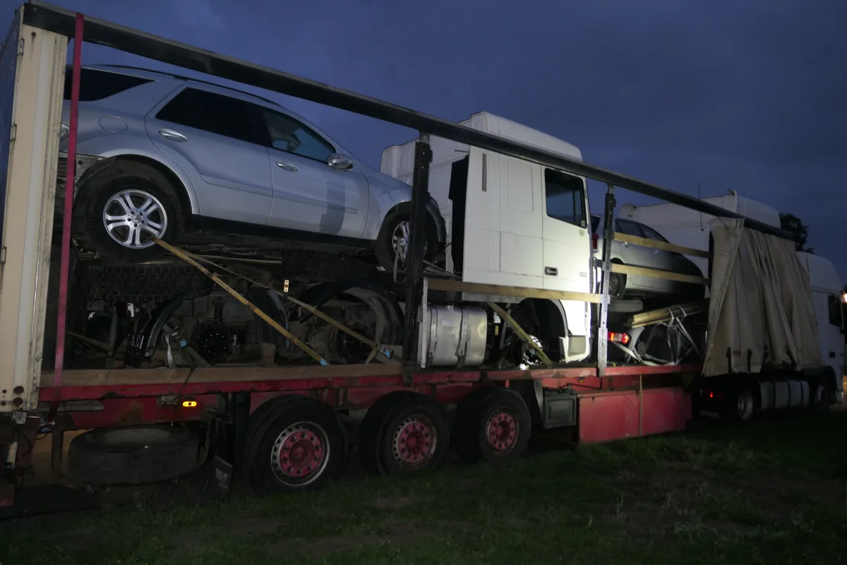 Ein Transporter mit mehreren Autos steht in der Abenddämmerung auf einem LKW-Anhänger. Der Himmel ist dunkel.