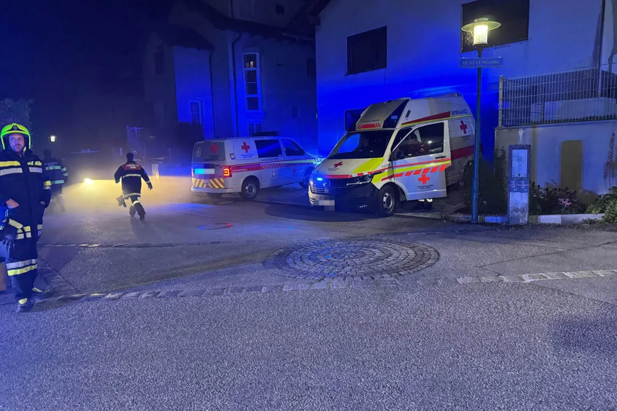 Zwei Rettungsfahrzeuge mit Blaulicht stehen in einer dunklen Straße. Einsatzkräfte sind ebenfalls vor Ort.
