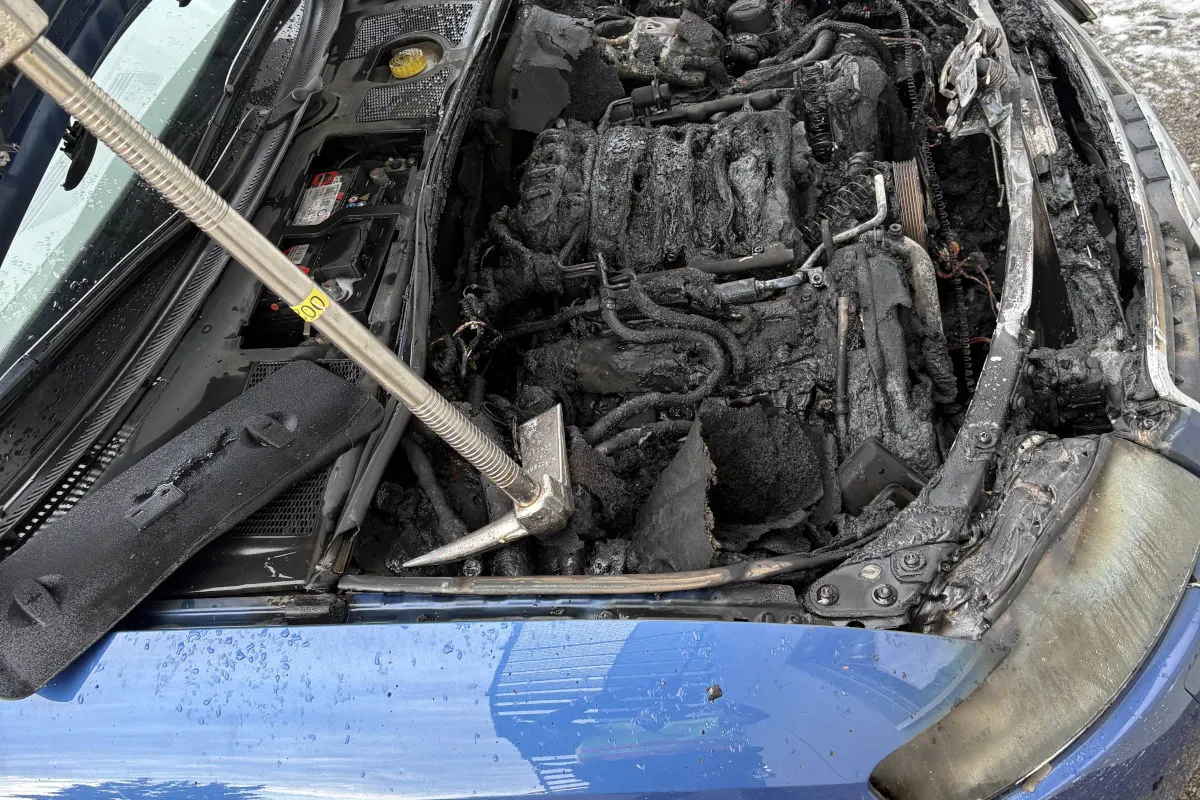 Detailaufnahme eines ausgebrannten Motorraums: die Motorteile sind stark verbrannt und schwarz, mit sichtbaren Brandschäden.