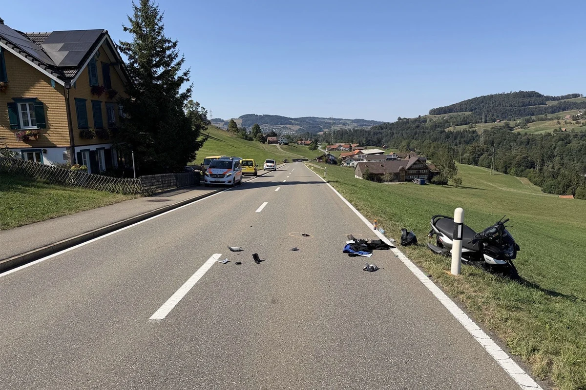 Auf einer Landstraße liegen Trümmerteile verteilt; ein beschädigter Roller steht am Straßenrand. Im Hintergrund sind einige Fahrzeuge zu sehen.