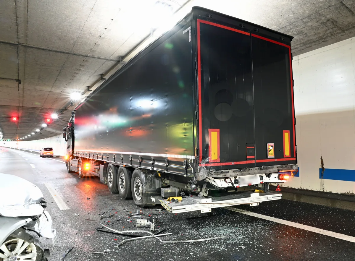 Ein schwarzer Lkw steht im Tunnel, umgeben von verstreuten Trümmern und einem beschädigten Fahrzeugheck. Im Hintergrund sind weitere Autos zu sehen.