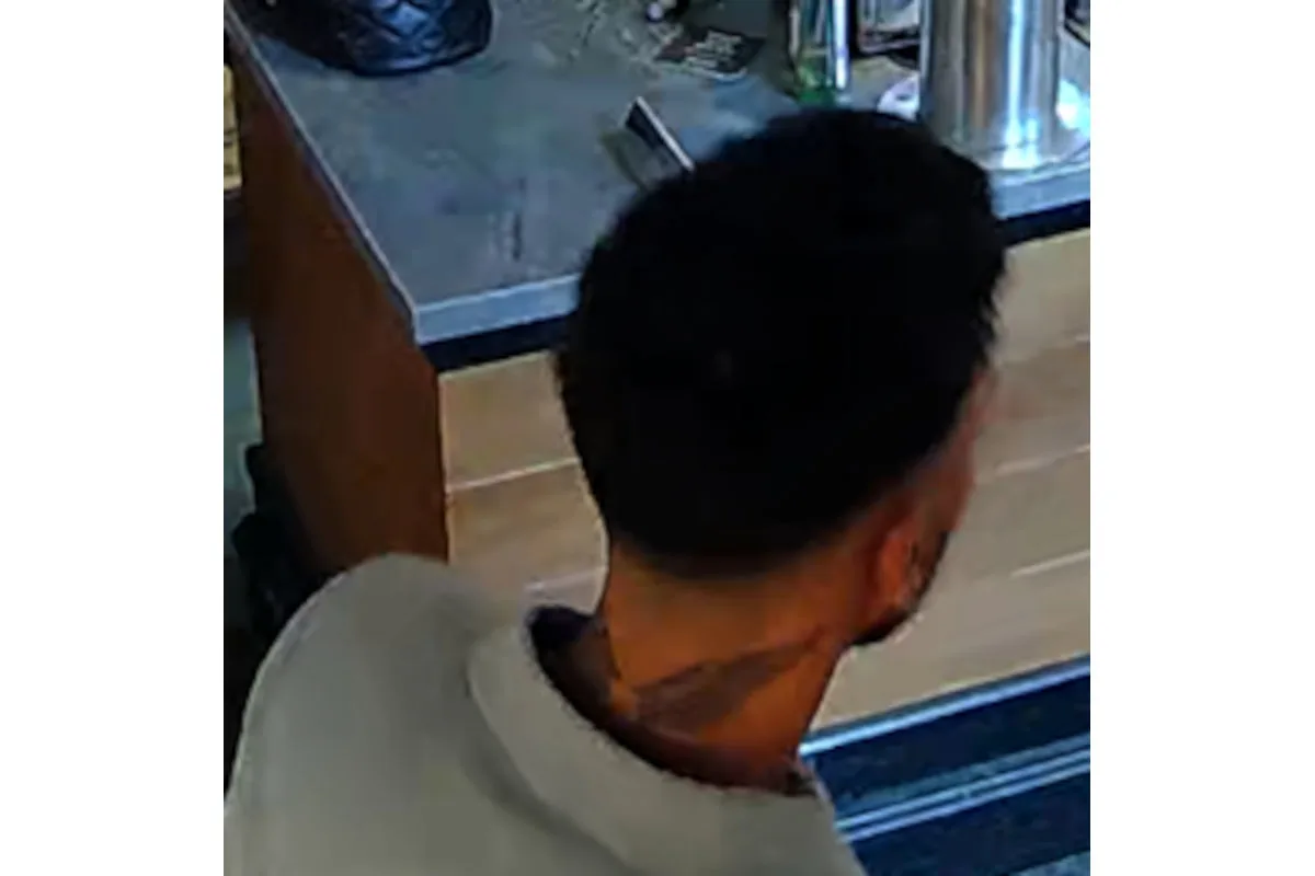 Das Bild zeigt eine Person von hinten, vermutlich in einem Geschäft, aufgenommen von einer Überwachungskamera.