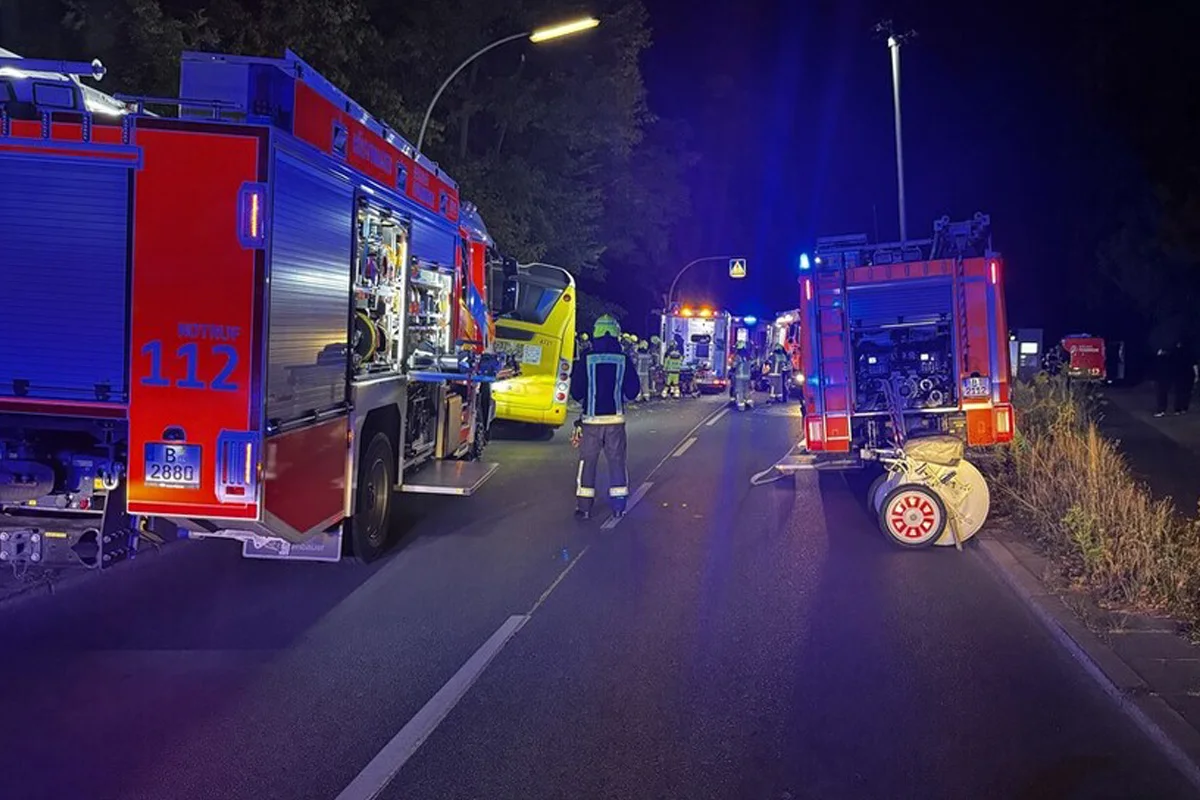 Mehrere Feuerwehrfahrzeuge stehen mit eingeschaltetem Blaulicht auf einer Straße. Feuerwehrleute sind vor Ort aktiv.