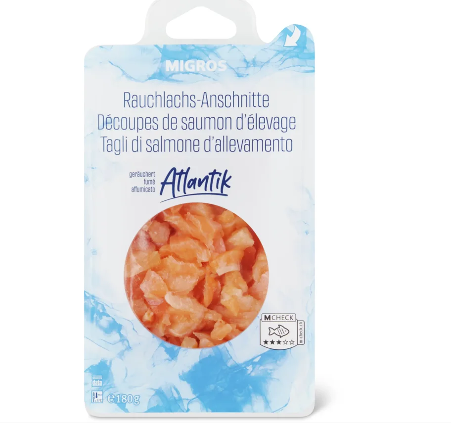 Eine Plastikverpackung mit der Aufschrift 'Migros Rauchlachs-Anschnitte' zeigt geschnittenen Lachs. Das Etikett enthält Informationen in mehreren Sprachen.