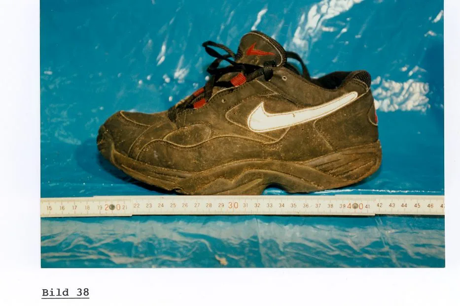 Ein einzelner, dreckiger Sportschuh liegt auf einer blauen Plastikunterlage, daneben ein Maßstab zur Größenbestimmung.