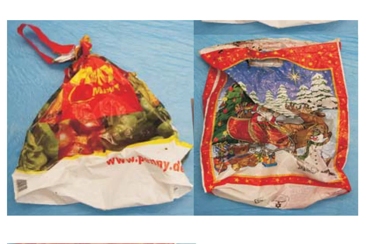 Zwei Plastiktüten liegen auf einem blauen Hintergrund. Die linke Tüte ist von Penny mit Obstmotiv, die rechte hat ein weihnachtliches Motiv mit Schlitten.