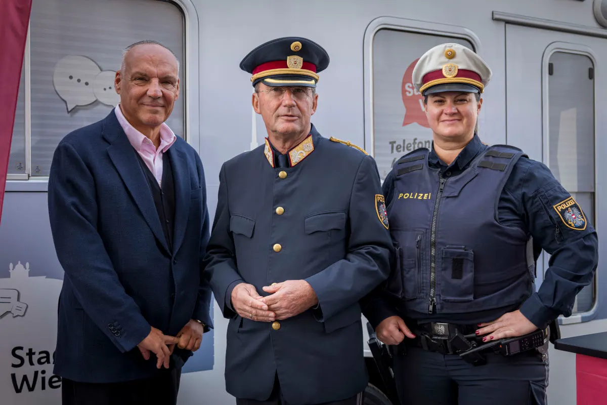 Drei Personen stehen gemeinsam vor einem Gebäude, zwei davon tragen eine österreichische Polizeiuniform.