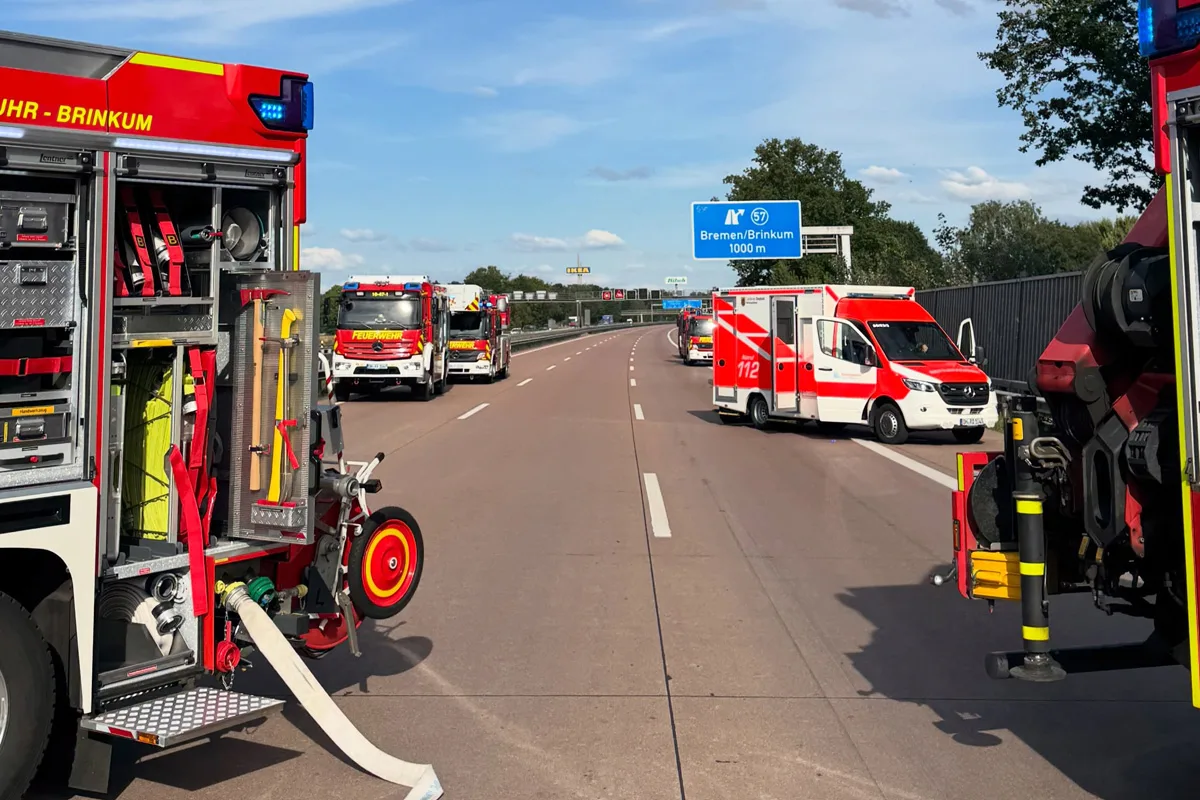 Mehrere Feuerwehrfahrzeuge stehen auf einer Autobahn, die Beschilderung zeigt Richtung Bremen, blauer Himmel.