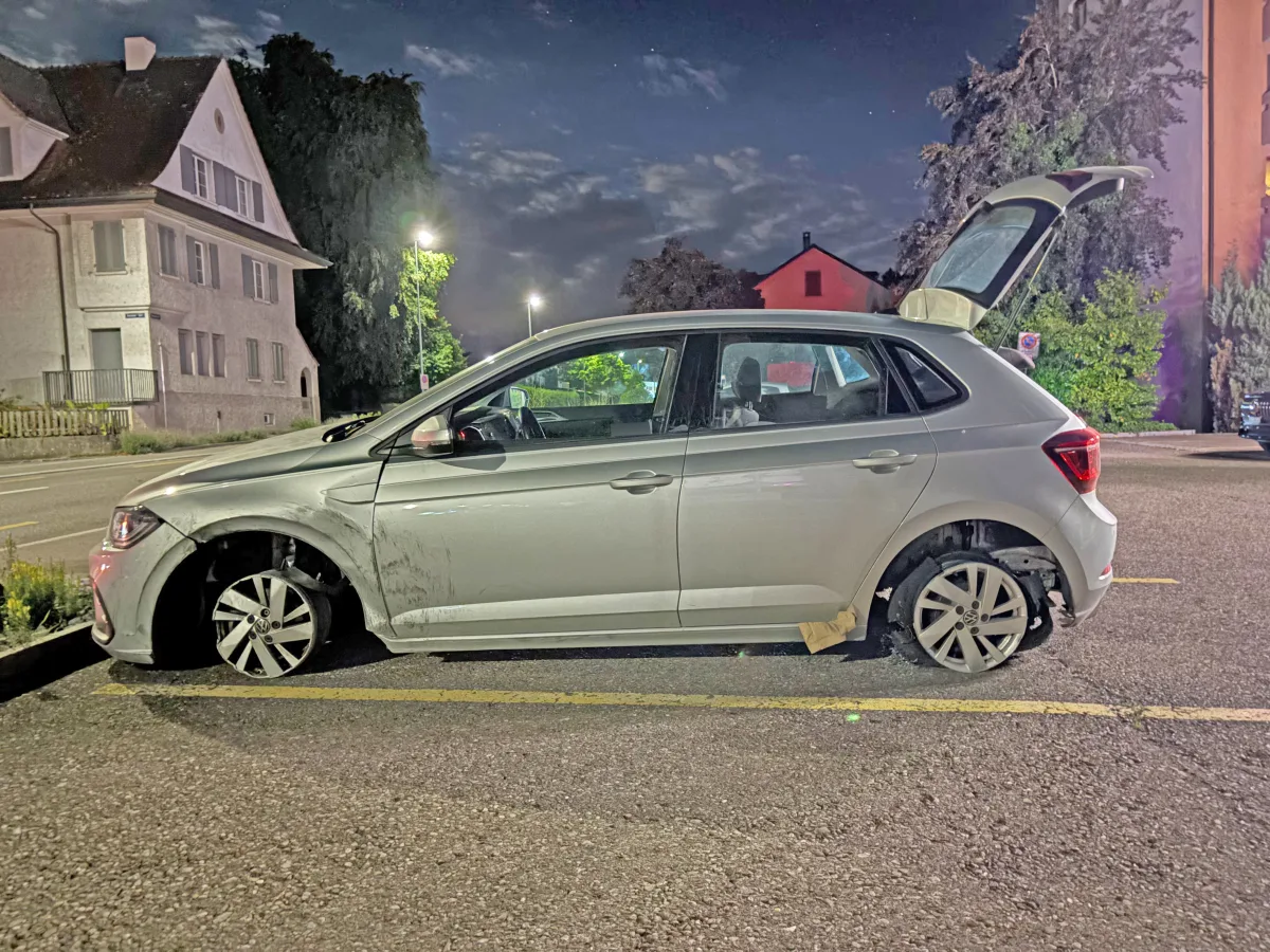 Ein silbernes Auto steht auf einem Parkplatz mit geöffnetem Kofferraum. Das Fahrzeug scheint vorne beschädigt zu sein.
