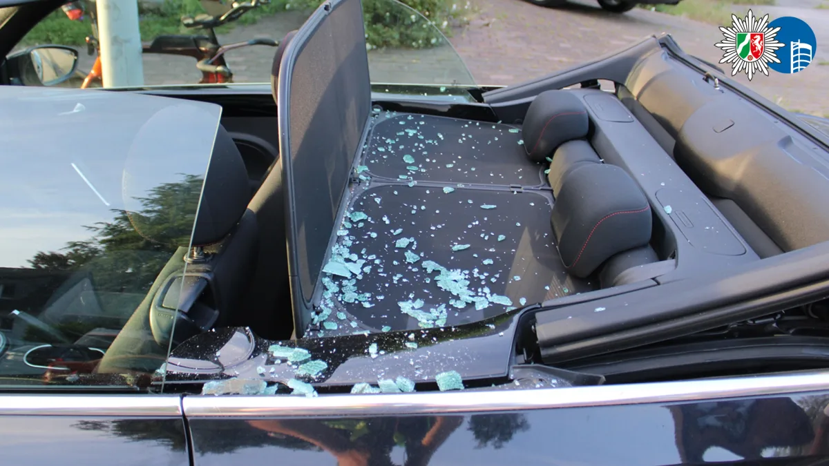 Die Rückbank eines Cabrios ist mit zerbrochenem Glas übersät. Das Dach des Fahrzeugs ist geöffnet.