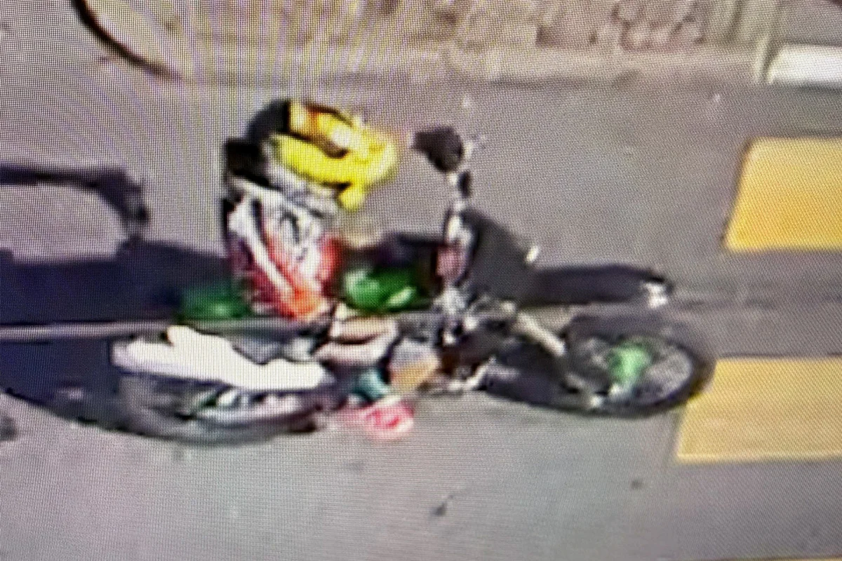 Ein Motorradfahrer mit einem gelben Helm fährt auf einer asphaltierten Straße. Die Szene ist aus der Vogelperspektive aufgenommen.