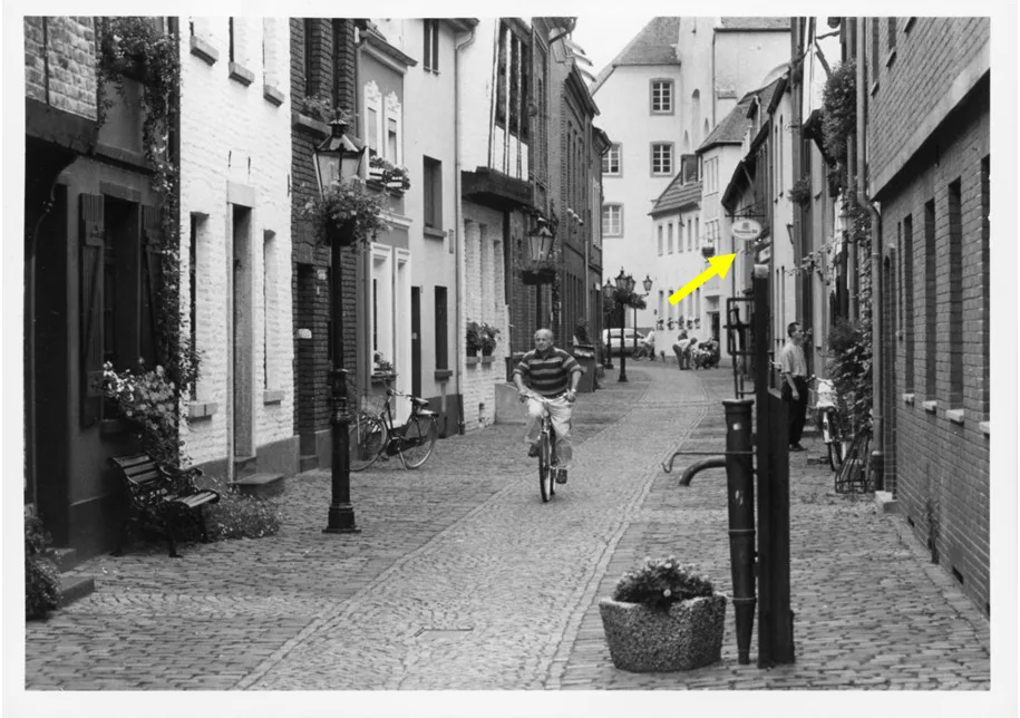 Ein Mann auf einem Fahrrad fährt durch eine schmale, gepflasterte Gasse in der Altstadt. Links und rechts sind Backsteingebäude zu sehen.