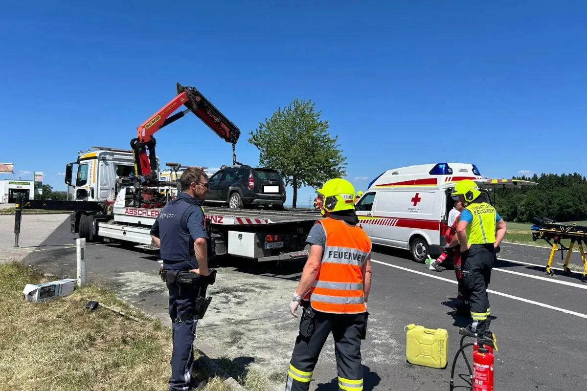 Ein Abschleppwagen hebt ein Auto, daneben stehen Feuerwehrkräfte und ein Krankenwagen bereit.