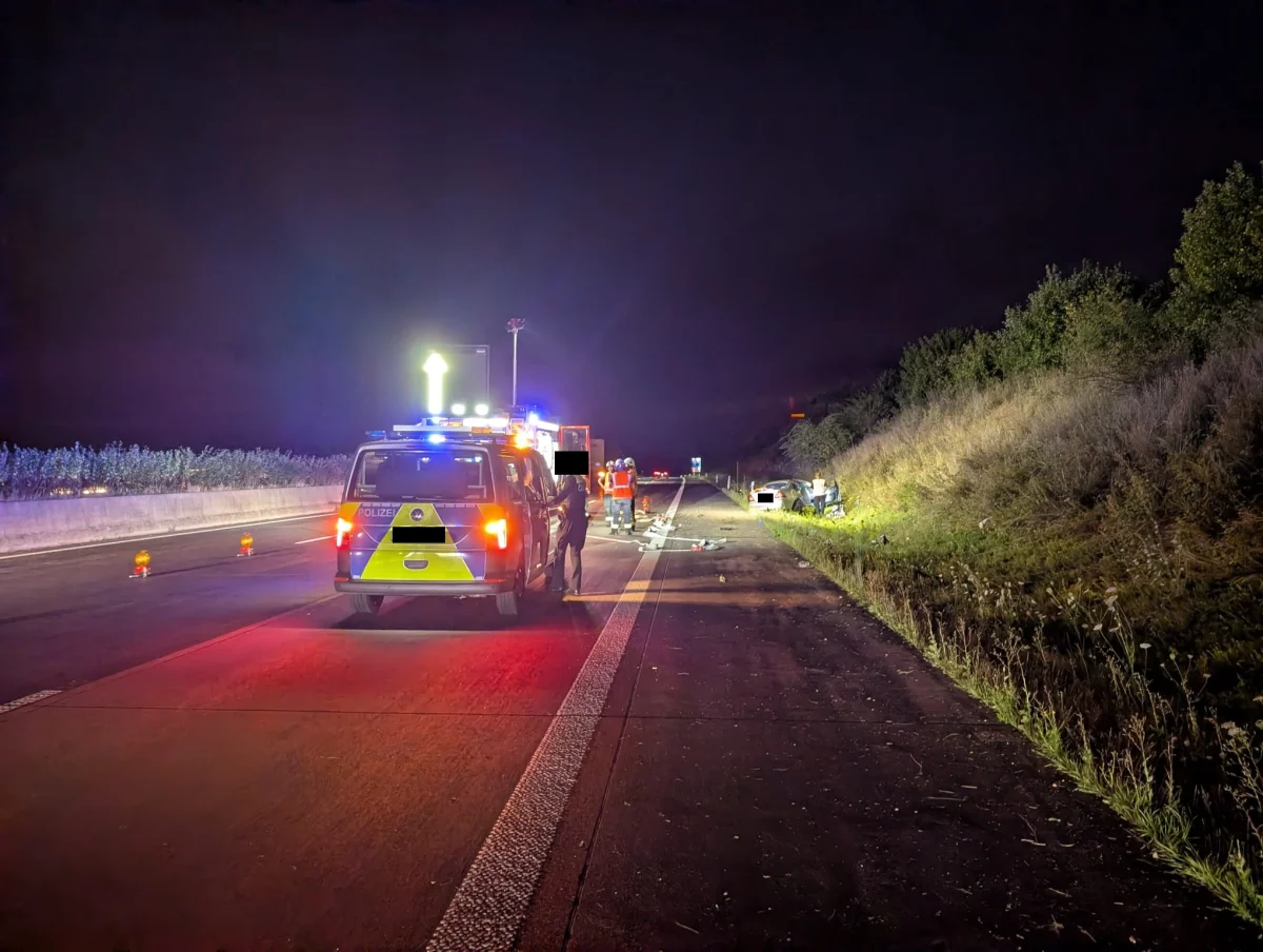 Bei Nacht stehen mehrere Einsatzfahrzeuge auf der Autobahn, ein Unfallfahrzeug ist auf dem Grünstreifen sichtbar.