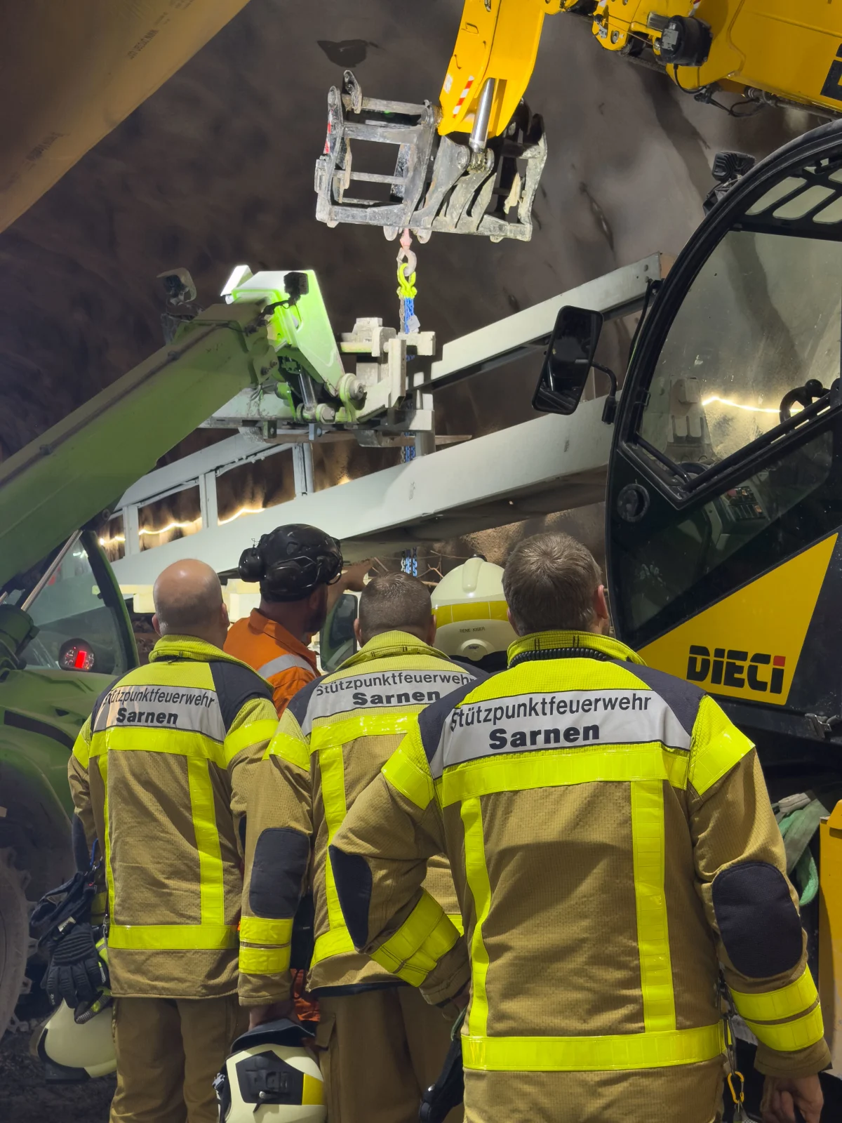 Mehrere Feuerwehrleute der Stützpunktfeuerwehr Sarnen stehen in einem Tunnel und beobachten Hebemaschinen bei einer Bergung.
