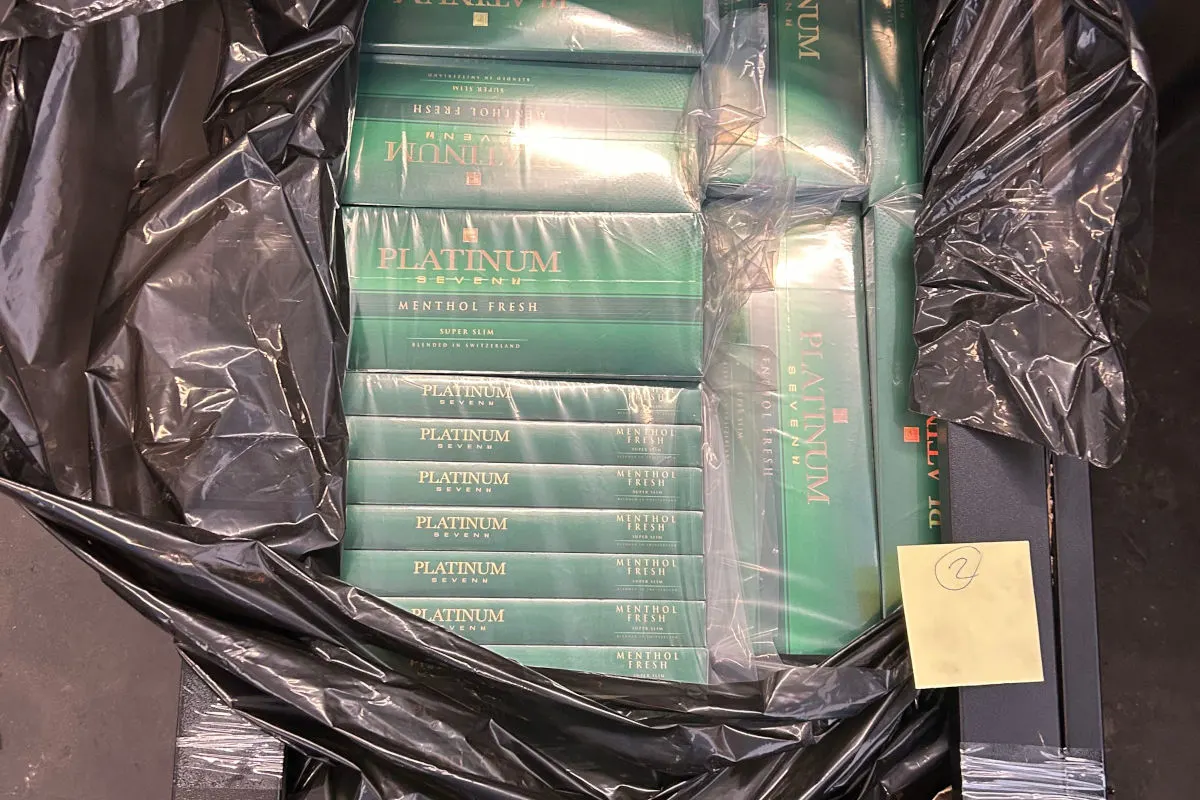 Mehrere Zigarettenschachteln der Marke Platinum Seven Menthol Fresh sind in einem schwarzen Plastiksack zu sehen. Die Schachteln sind in Reihen gestapelt und teilweise in Plastik eingewickelt.