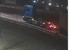 Ein blauer Lkw fährt nachts auf einer schlecht beleuchteten Straße. Es sind keine weiteren Fahrzeuge in der Nähe.