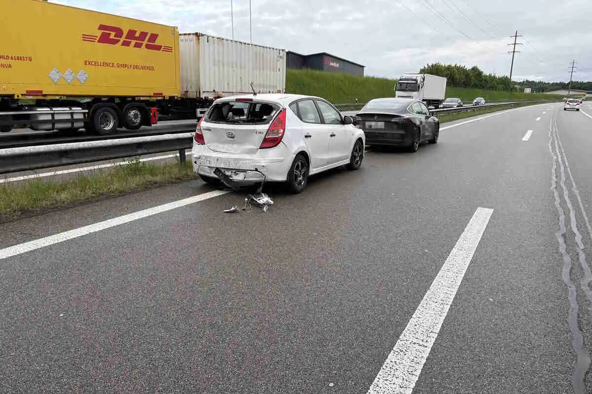 Zwei beschädigte Fahrzeuge stehen auf einer Autobahnspur. Im Hintergrund sind LKWs zu sehen.
