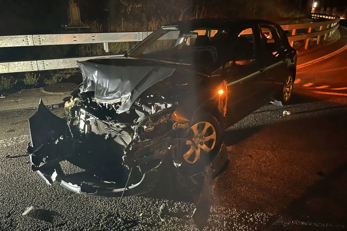 Ein Auto mit erheblichen Frontschäden steht auf einer Straße. Teile der Karosserie sind herausgerissen. Es ist Nacht.