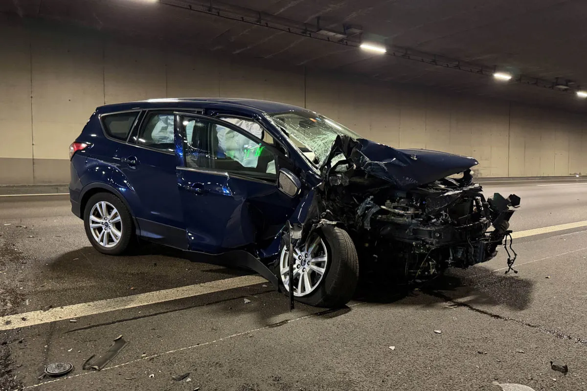 Ein blaues Auto steht mit schwer beschädigter Frontpartie in einem Tunnel. Der Asphalt ist mit Trümmern übersät.