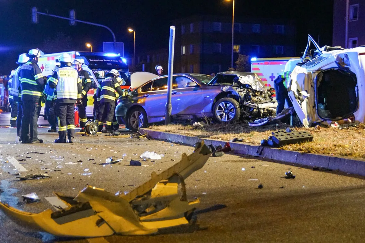 Bei Nacht ereignete sich ein schwerer Unfall auf einer Kreuzung. Feuerwehrleute kümmern sich um die Absicherung der Unfallstelle, wobei zwei stark beschädigte Fahrzeuge deutlich sichtbar sind.
