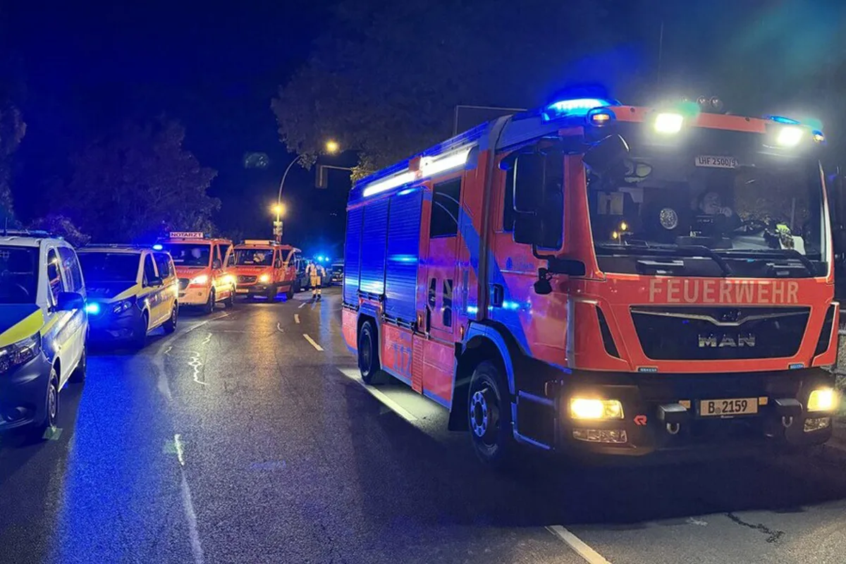 Ein Feuerwehrauto mit eingeschaltetem Blaulicht steht auf einer nächtlichen Straße. Im Hintergrund sind weitere Einsatzfahrzeuge zu sehen.
