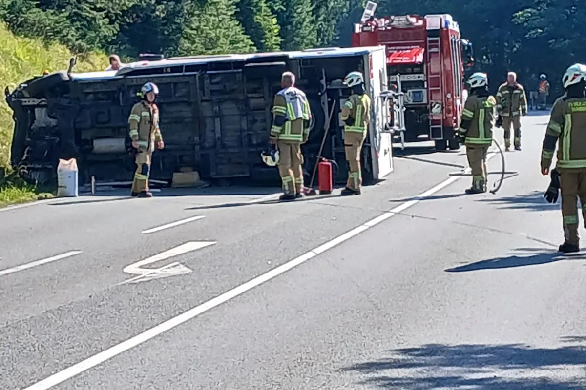Ein umgekippter Bus liegt auf der Seite auf einer Landstraße. Mehrere Feuerwehrleute sind vor Ort im Einsatz.