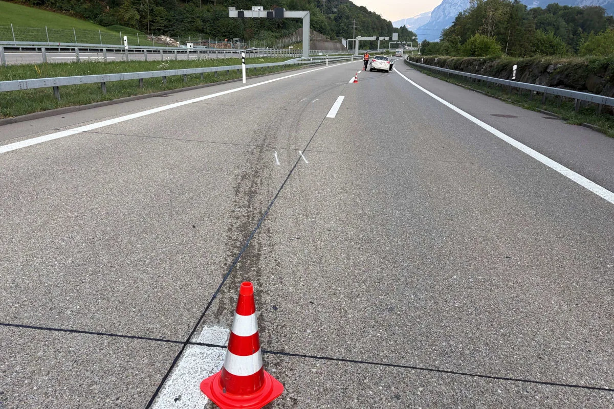 Ein weißes Auto steht auf einer leeren Autobahn neben weißen Markierungslinien und roten Verkehrshütchen.