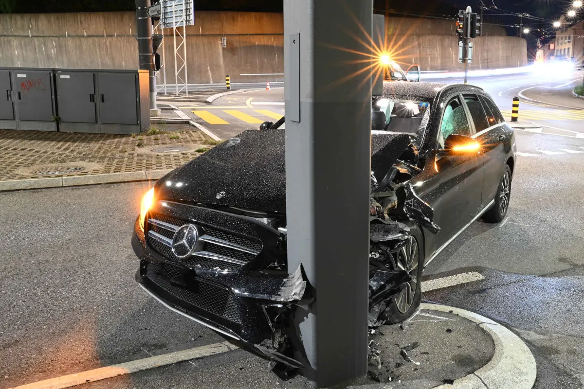 Ein schwarzer Mercedes ist frontal mit einem Mast kollidiert. Die Nachtaufnahme zeigt deutliche Schäden am Fahrzeug.
