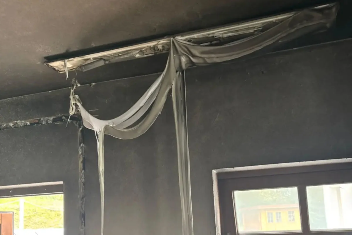 Eine durch einen Brand beschädigte Deckenleuchte mit herabhängenden, geschmolzenen Materialien und Rußspuren an der Decke.