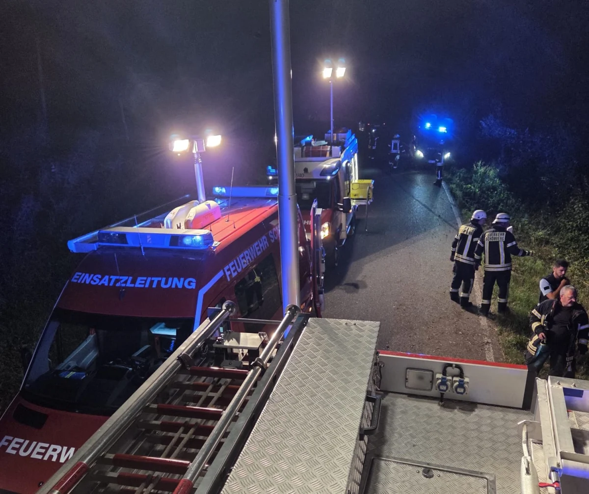 Mehrere Feuerwehrautos mit Blaulicht stehen bei Nacht auf einer Straße, Einsatzkräfte sind in Aktion.