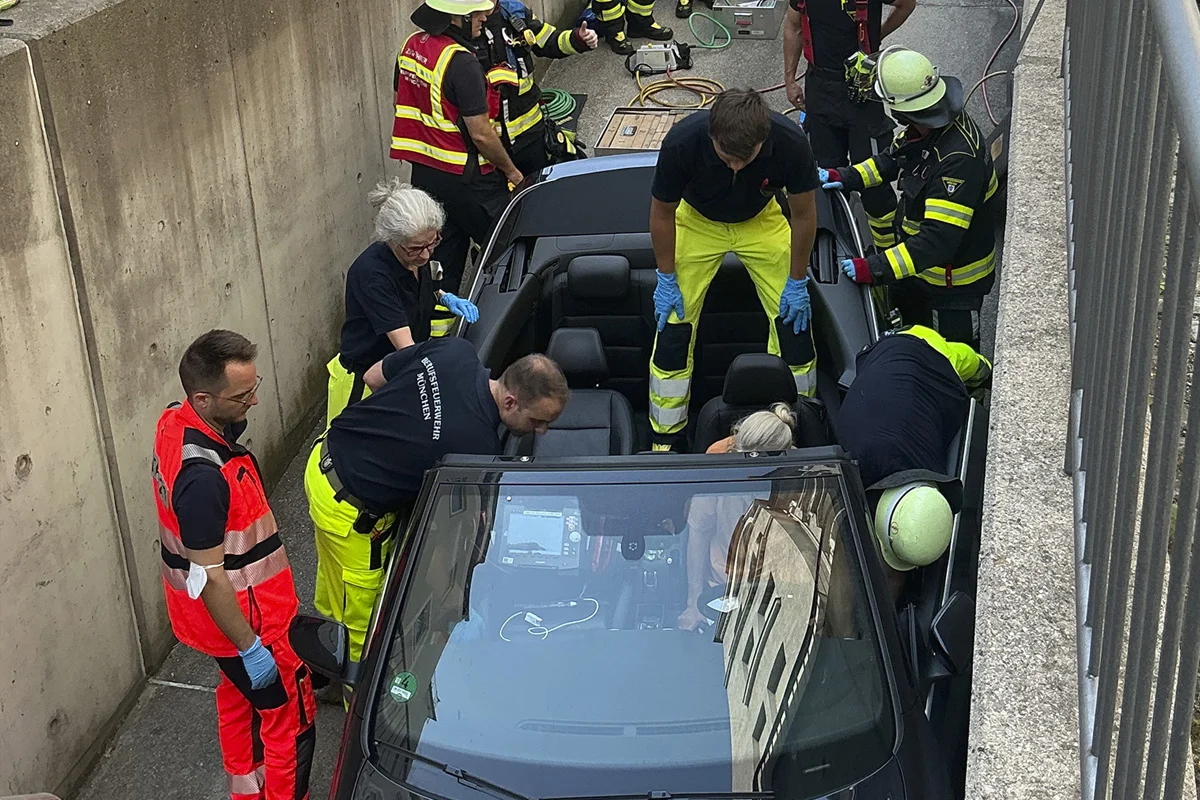 Mehrere Rettungskräfte sind um ein Auto in einem engen Kanal versammelt. Sie arbeiten daran, die Insassen zu befreien.